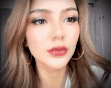 a close up of a woman 's face with red lips and gold hoop earrings
