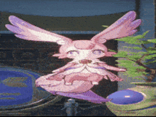 a pink bunny with purple wings is sitting on a table