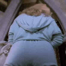 a woman in a blue hoodie is standing in a room