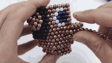 a person is holding a toy made of copper beads that looks like an american flag