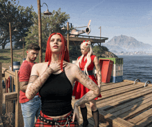 a woman with red hair is standing next to a man and another woman