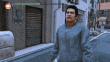 a man in a blue sweater is walking down a street in front of a building that says ' a ' on it