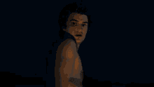 a man without a shirt is looking at the camera in a dark room