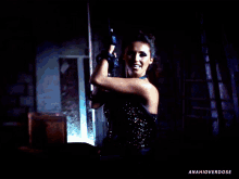 a woman in a black dress is dancing in a dark room with the words anahioverdose below her