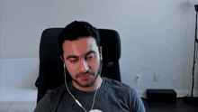 a man wearing headphones is sitting in a chair and looking at the camera .