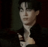a man in a black shirt is adjusting his shirt collar .