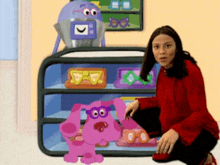 a woman in a red shirt kneeling next to a purple dog