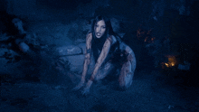 a woman with long black hair is kneeling down in the water