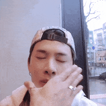 a man wearing a hat and a ring is covering his face