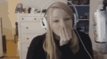 a woman wearing headphones is covering her mouth