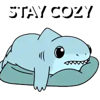 a cartoon shark is laying on a pillow with the words stay cozy above it