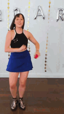 a woman in a blue skirt is dancing in front of balloons that say " rap "