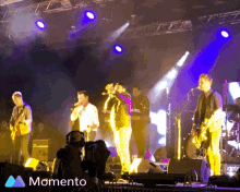 a group of musicians on stage with the word momento in the corner