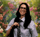 a woman wearing glasses and a tie is smiling in front of a garden