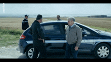 three men are standing in front of a car that says meriel