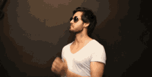 a man wearing sunglasses and a white t-shirt has a tattoo on his neck