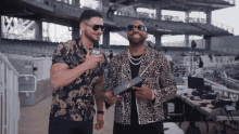 two men are standing next to each other and one has a microphone that says aew