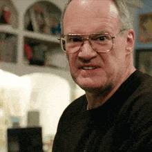 a man wearing glasses and a black shirt looks angry