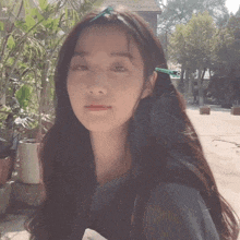 a woman wearing a headband with a green ribbon on it looks at the camera