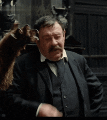 a man in a suit and tie is holding a stuffed animal