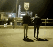 two people walking in front of a sign that says no parking