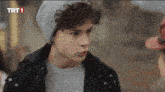a young man wearing a beanie and a sweater with trt1 written on the bottom right