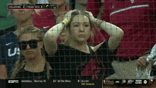 a woman behind a fence watching a baseball game