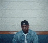 a man wearing a hat with the letter m on it sits on a bench