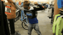 a man in a blue shirt is standing in a store with a bicycle in the background