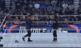 two men in a wrestling ring with a sign that says " just for a thima "