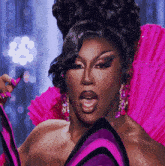 a drag queen is wearing a purple and pink costume