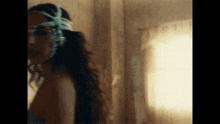 a woman with a headband on her head is standing in front of a window in a room .