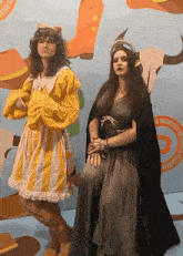 a man in a yellow and white striped dress and a woman in a black dress are posing for a picture