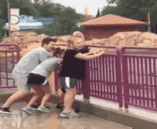a group of children are standing next to a purple fence .