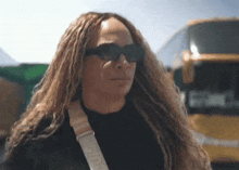 a woman with dreadlocks is wearing sunglasses and a black shirt .