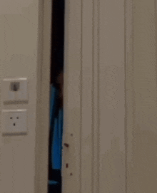 a man is peeking out from behind a door .