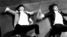 a black and white photo of two men in suits dancing .