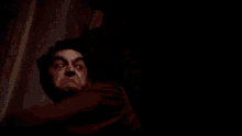 a man is crying while standing next to a wall in a room .
