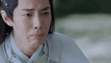 a man with long hair and a white shirt is making a sad face