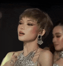 a woman with short hair is wearing a necklace and earrings