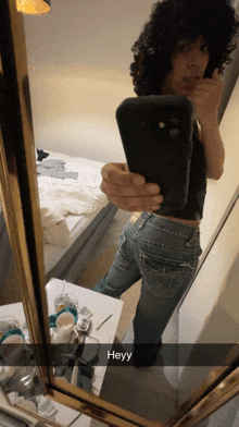 a person taking a selfie in front of a mirror with heyy written on the bottom right