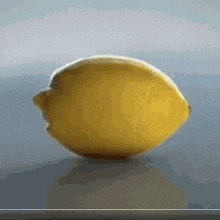 a yellow lemon is sitting on a table with a gray background