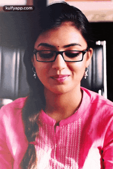 a woman wearing glasses and a pink shirt is smiling for the camera