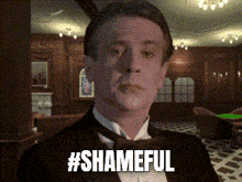 a man in a tuxedo has the hashtag #shameful written on his face