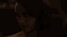 a close up of a woman 's face in the dark with a pearl necklace .