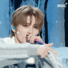 a close up of a person singing into a microphone with the letters mbc on the bottom