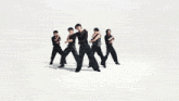a group of young men in black shirts are dancing
