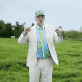 a man in a suit and tie is standing in a grassy field and making a funny face .