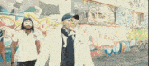 a group of people are dancing in front of a wall with graffiti on it that says k.k.