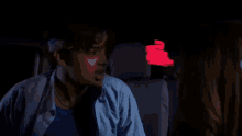 a man with a bandana on his head is sitting in a dark room with the name kd written on a red background